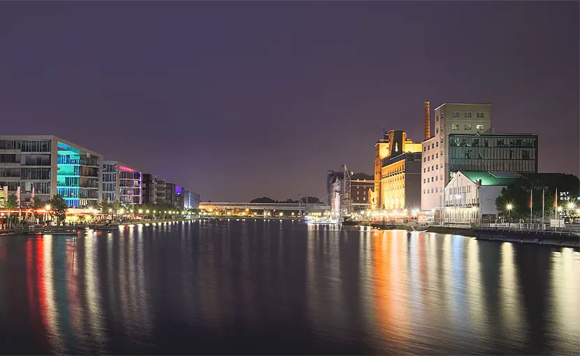 Blick auf den beleuchteten Rhein-Nebenarm am Innenhafen in Duisburg bei Nacht.